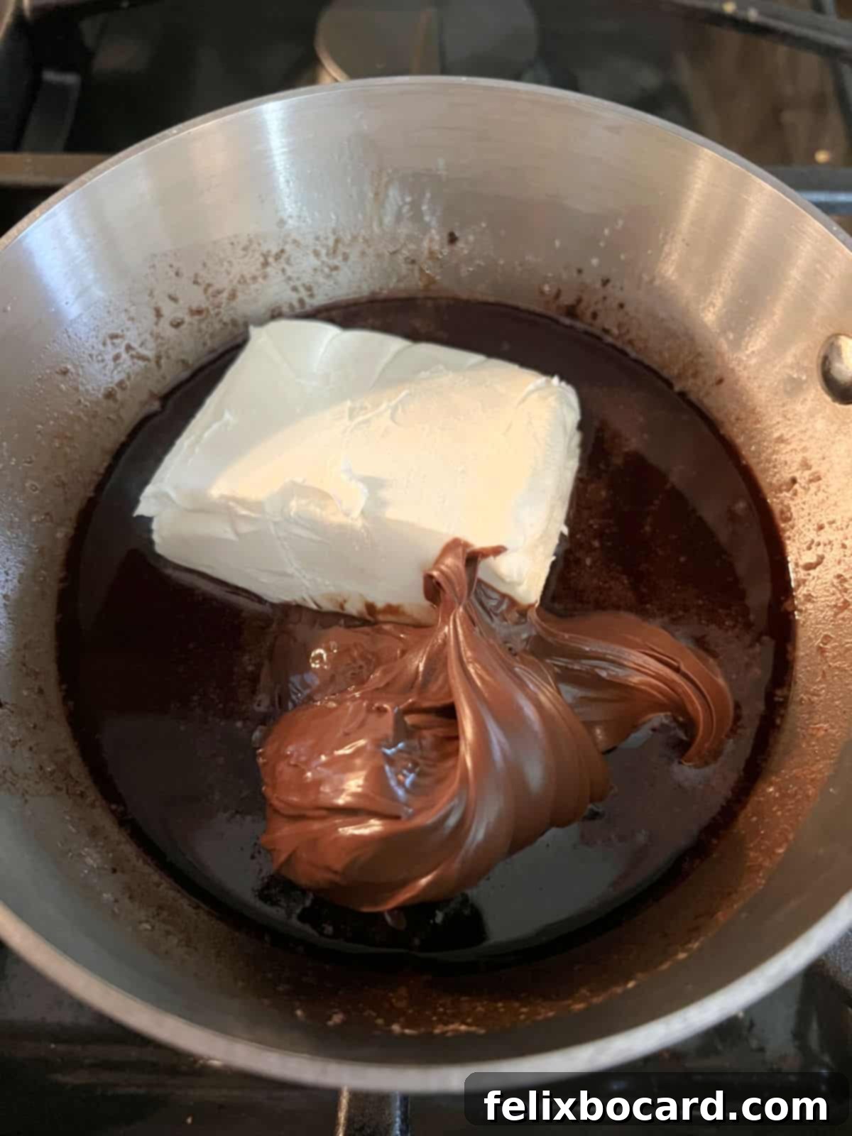 Adding softened cream cheese and sugar-free cocoa-hazelnut spread to the saucepan with melted butter, sweetener, and cocoa powder.