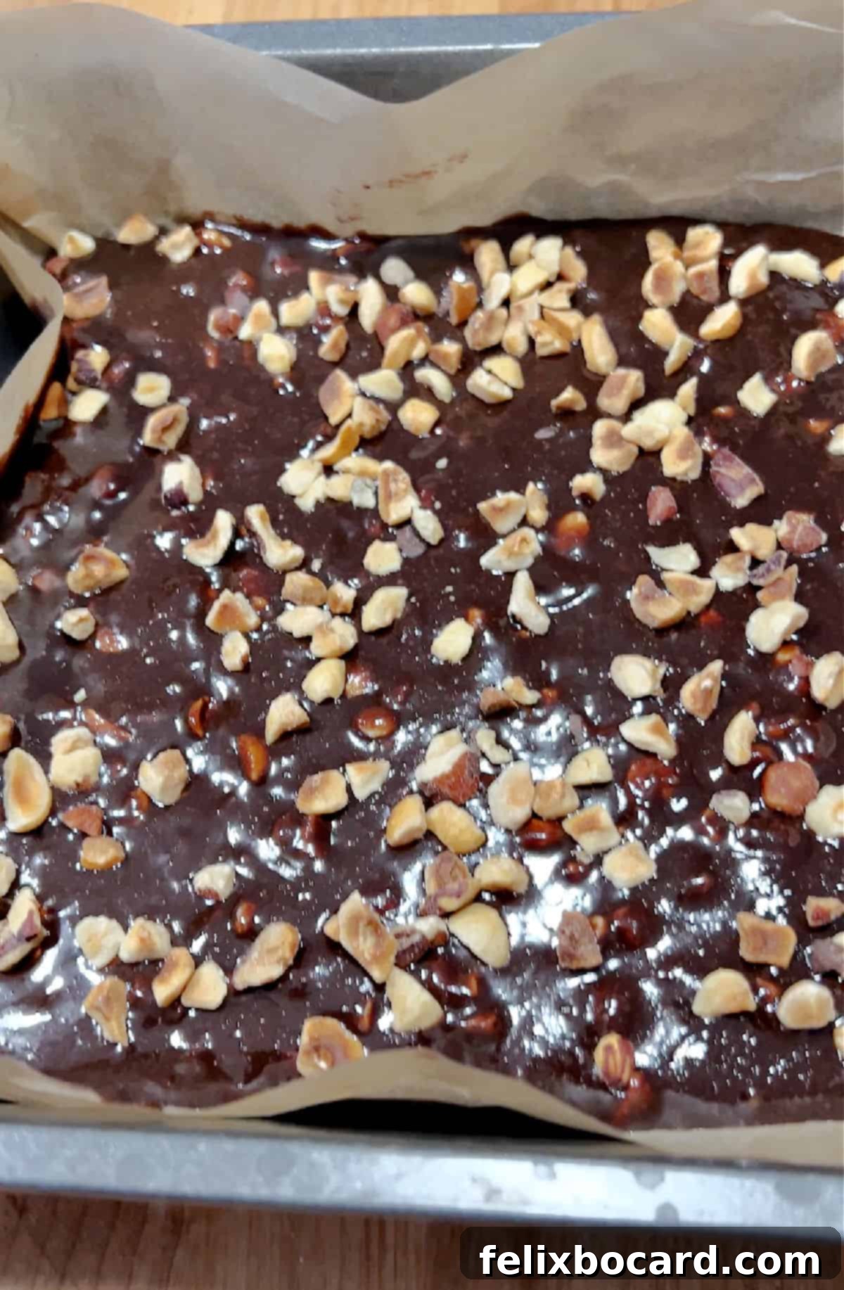 A pan filled with keto Nutella snacks, showcasing both hazelnuts mixed within the rich chocolate base and sprinkled generously on top for added texture.