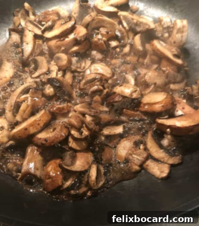 Sliced mushrooms cooking in a hot pan without oil, releasing their natural juices.