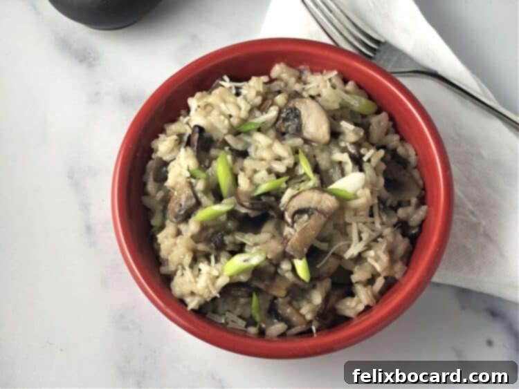 A close-up of creamy Mushroom Risotto in a small red bowl, with a fork.