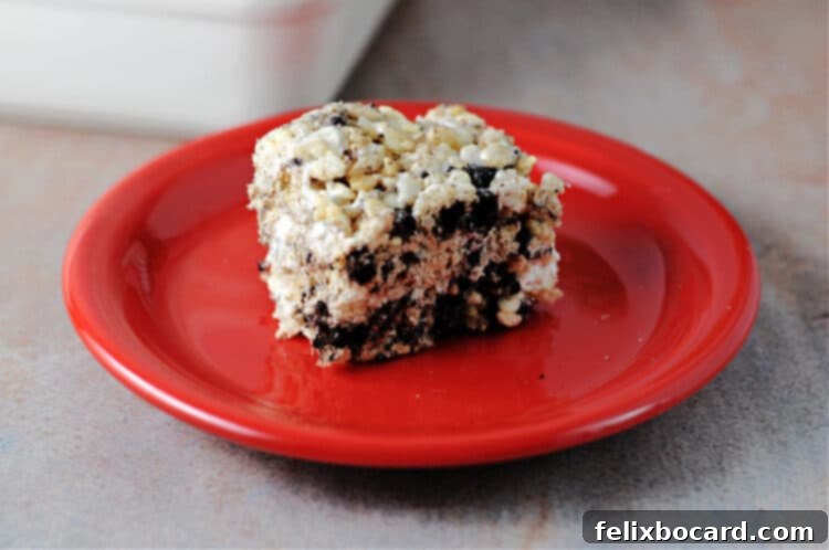 Oreo Cookies and Cream Krispie Bars 2 A square of delicious Oreo Krispies on a vibrant red plate, showcasing the crushed Oreo pieces within the marshmallow treat.