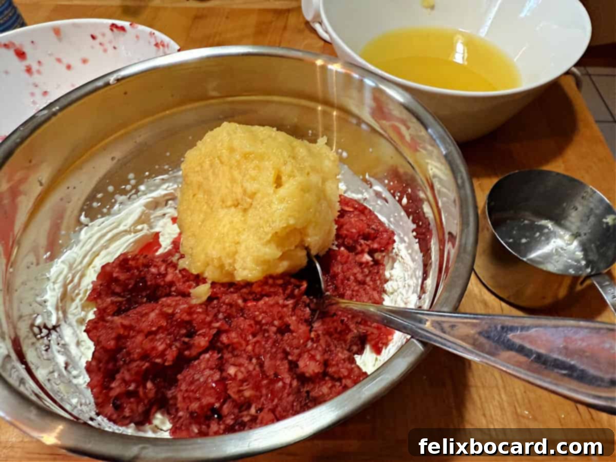 The minced fruit mixture being added to the freshly whipped cream in a large bowl.