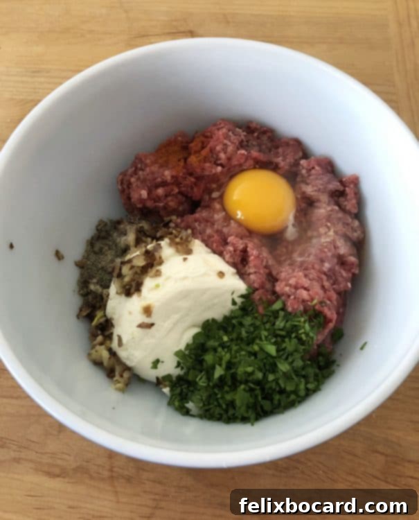 Various ingredients for making ricotta meatballs laid out on a wooden surface, including ground beef, ricotta cheese, onions, garlic, parsley, egg, and breadcrumbs.