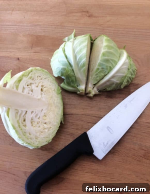A sharp knife and cabbage wedges ready for roasting on a cutting board, emphasizing precise cutting.
