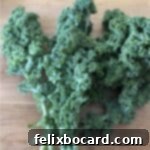 A vibrant bunch of fresh kale rests on a wooden cutting board, serving as the main ingredient for this simple massaged kale recipe.