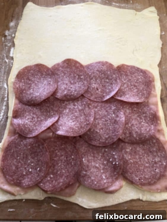 Salami and cheese layered on puff pastry for Stromboli