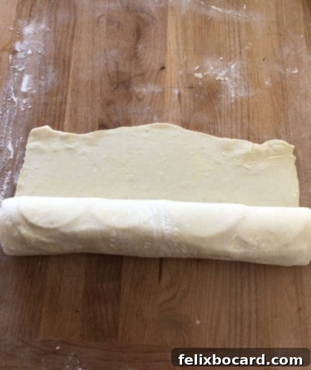 Rolling up the puff pastry filled with meat and cheese