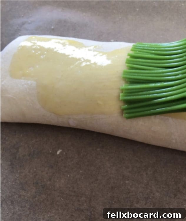 Brushing egg wash over the puff pastry Stromboli