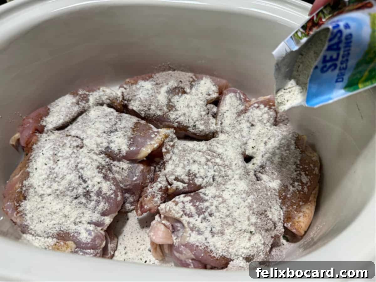 Raw chicken in crockpot with dry seasoning sprinkled on top.