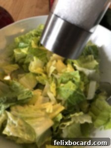 adding salt to the lettuce in the bowl