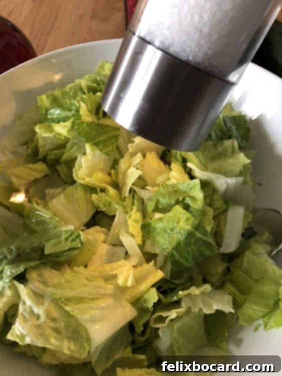 adding salt to the lettuce in the bowl