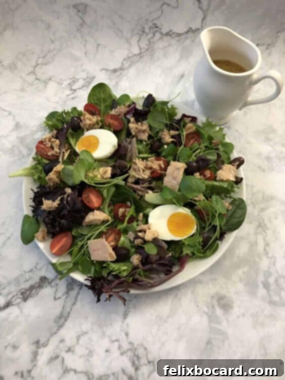 Nicoise salad with small pitcher of dressing nearby