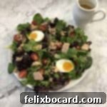 Nicoise salad with small pitcher of dressing nearby