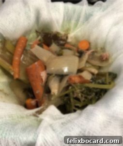 Cooked solids from bone broth, including bones and vegetables, being strained through a cheesecloth-lined colander.