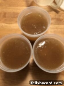 Three jars of freshly made bone broth, cooling and ready for storage, showcasing its rich golden color and healthy appearance.