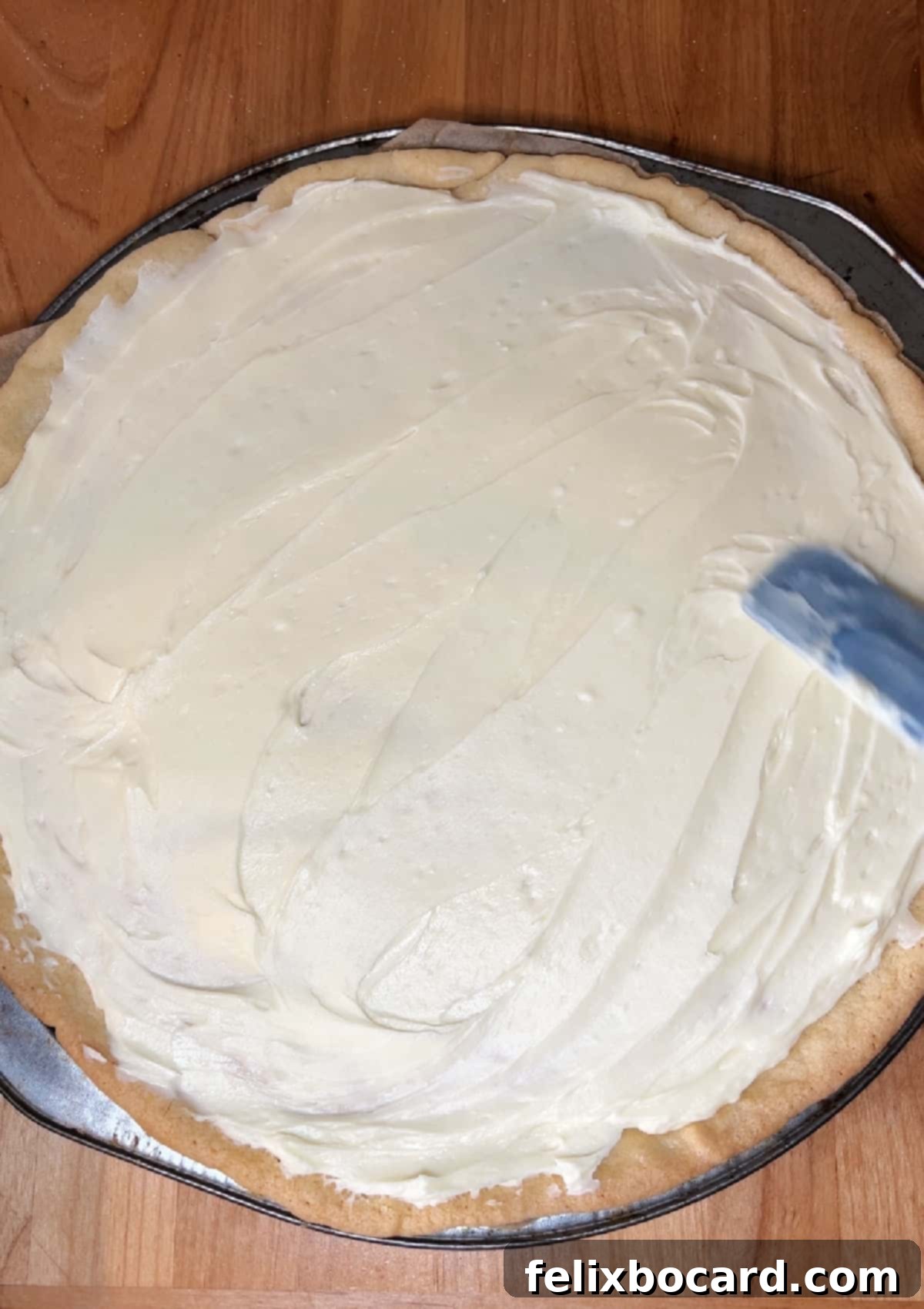 Spreading the cream cheese mixture on the cooled crust.