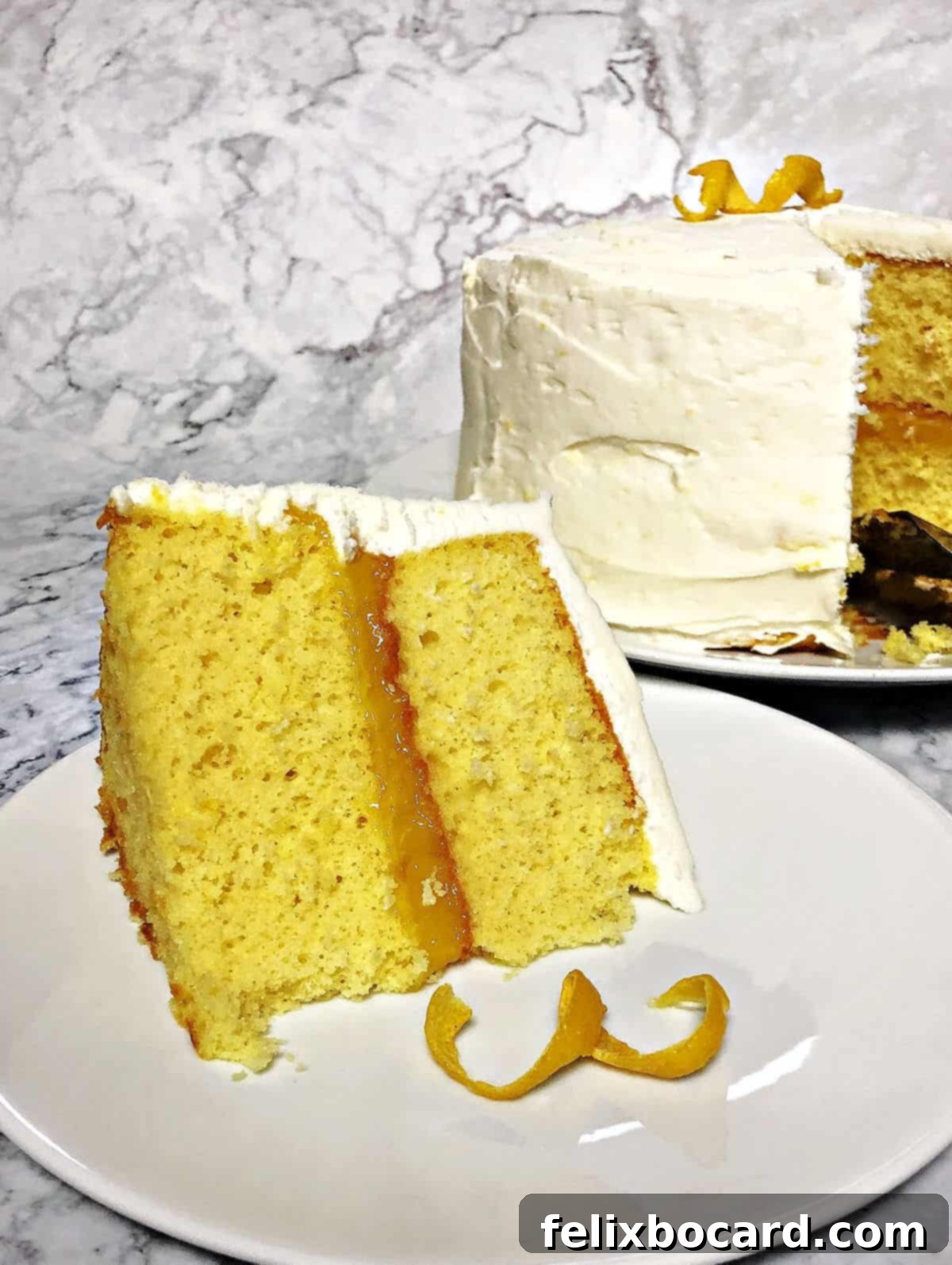 A perfect slice of Lemon Layer Cake, showcasing its beautiful layers, resting on a plate with a fork, ready to be eaten. The whole cake is blurred in the background.