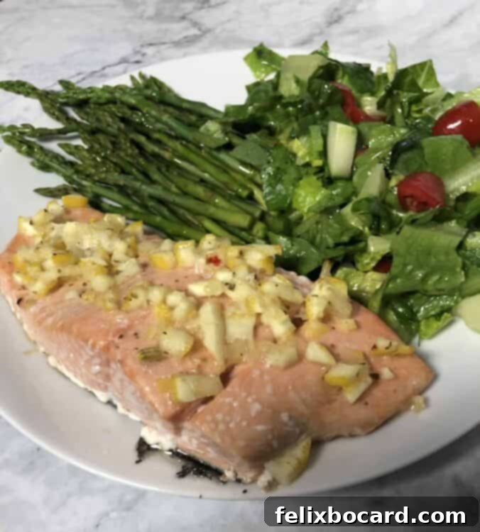 Plated salmon with whole lemon dressing, accompanied by fresh asparagus and a vibrant green salad, ready to be enjoyed.