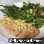 Plated salmon with whole lemon dressing, accompanied by fresh asparagus and a vibrant green salad, ready to be enjoyed.