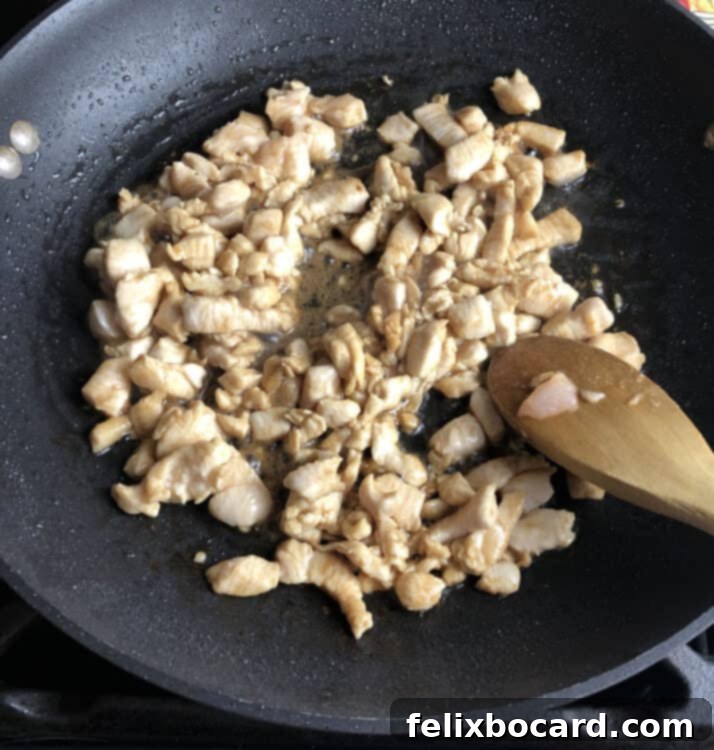 chicken being stir fried in a skillet