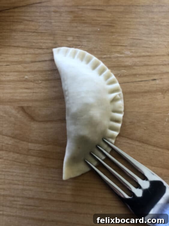 A person sealing the edges of a potsticker dumpling with the tines of a fork.