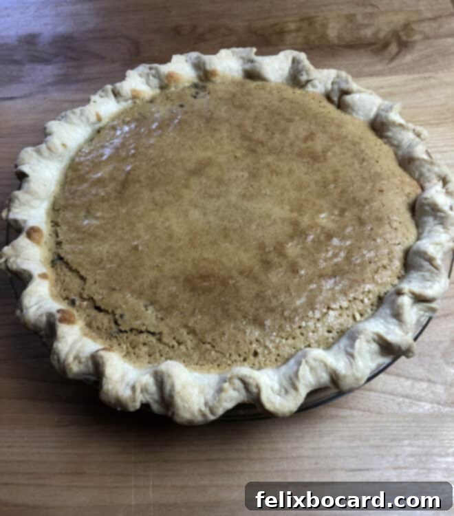 A close-up of a fully baked Chocolate Walnut Pie, showcasing its golden, crackled crusty top, indicating a perfectly set filling.