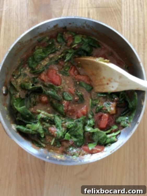Tomato and spinach sauce cooking in a saucepan, highlighting the vibrant colors and fresh ingredients coming together effortlessly.