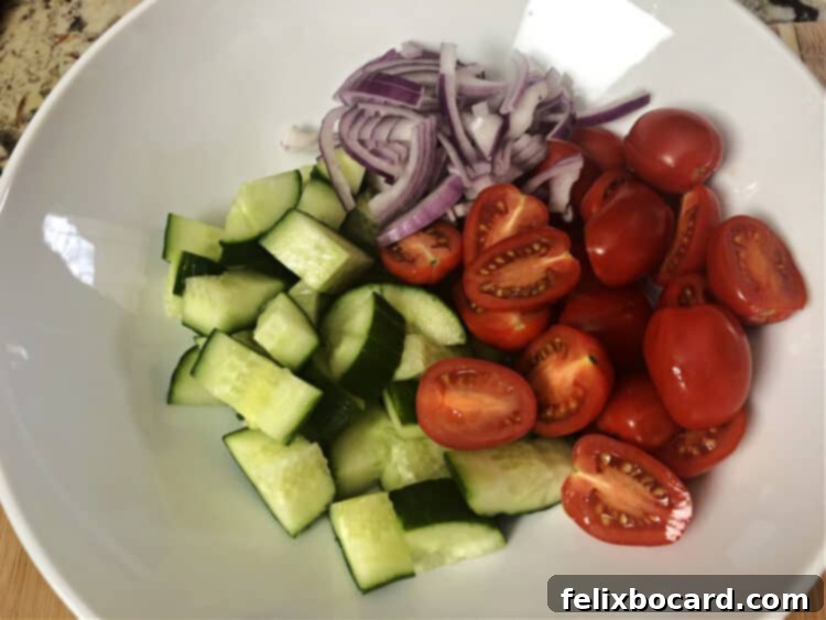 cut up tomatoes, cucumber and red onion in a bowl