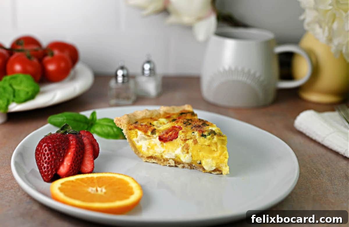 Slice of Caprese quiche on a plate garnished with a strawberry, slice of orange, and some basil.