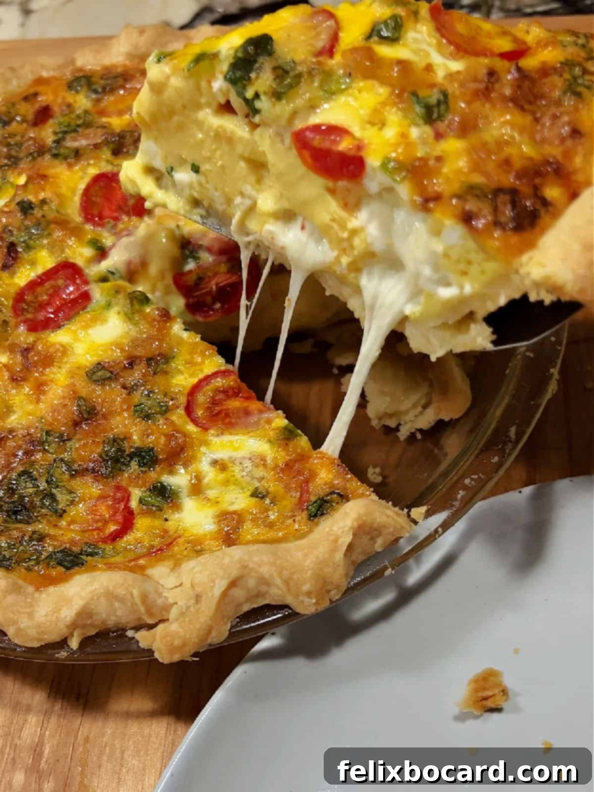 Lifting a piece of Caprese Quiche out of the pan.