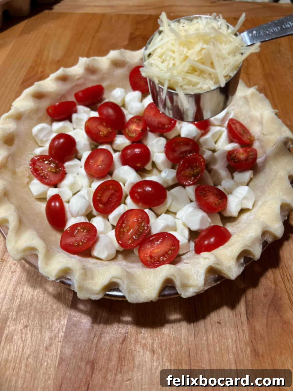 Adding Parmesan cheese to the pie crust with mozzarella and tomatoes.