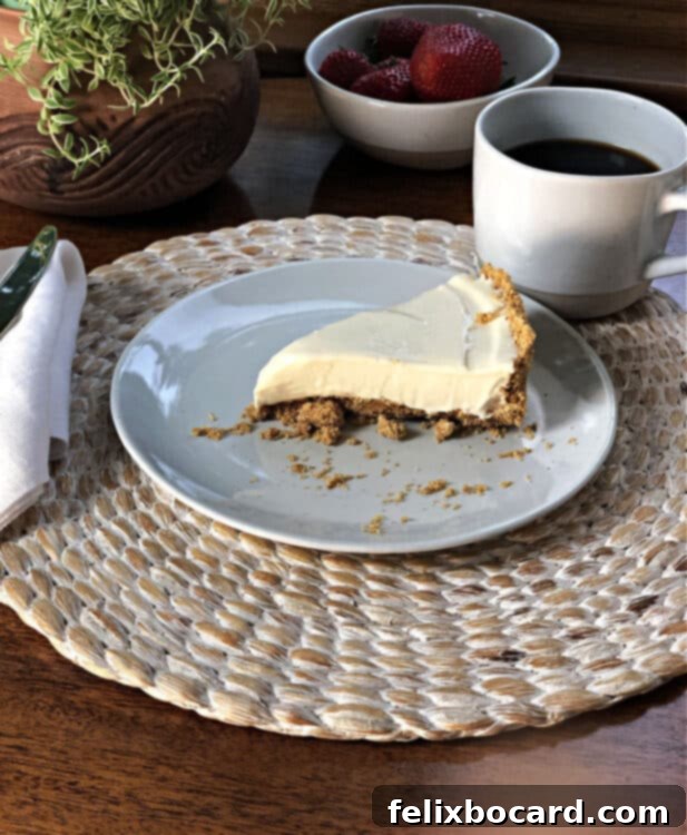 Oven-Free Cheesecake Delight 3 A pristine slice of plain no-bake cheesecake resting on a white plate, accompanied by a steaming cup of coffee, ready for a delightful morning or afternoon treat.