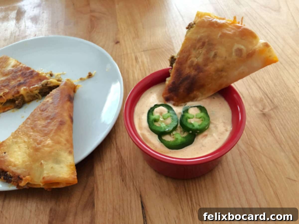 Copycat Taco Bell Creamy Jalapeno Quesadilla Sauce 6 A delicious piece of quesadilla being dipped into a bowl of the creamy jalapeño sauce, highlighting its perfect consistency.