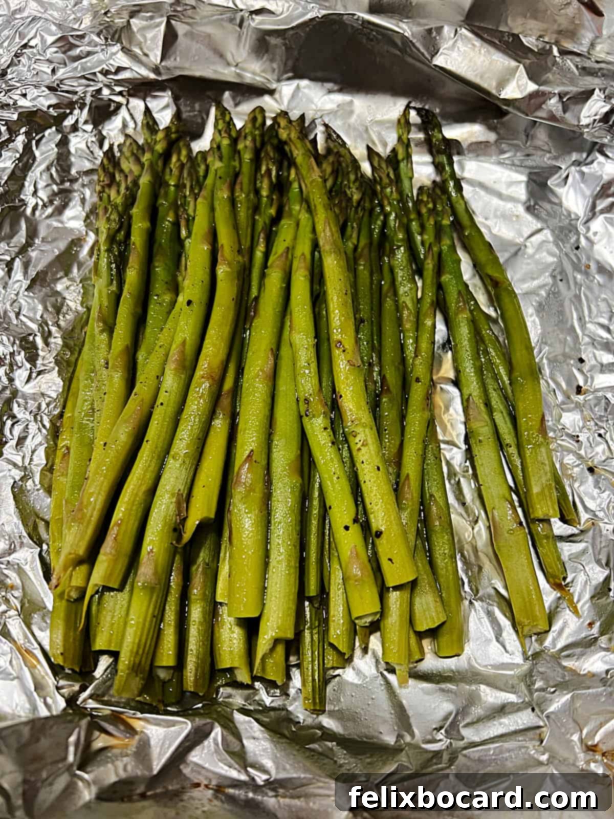 Open foil packet of grilled asparagus.
