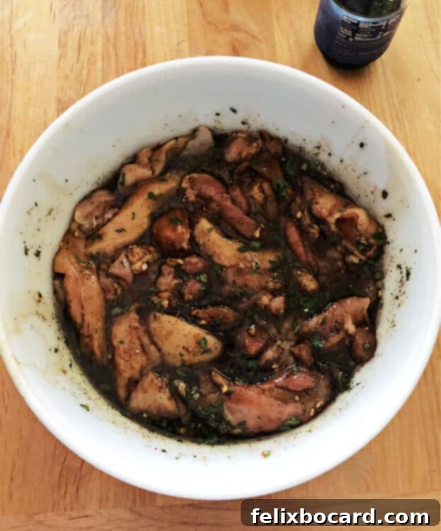 cut up chicken pieces soaking in marinade in a white bowl