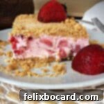 frozen strawberry dessert square on a small plate with a fresh strawberry garnish on top