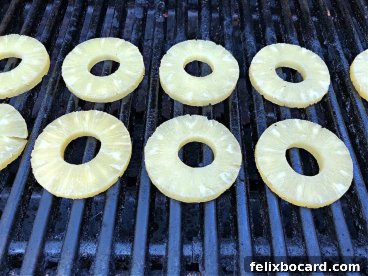 Sweet and Smoky Grilled Pineapple 3 Pineapple rings just starting to cook on the grill, showing slight char marks.