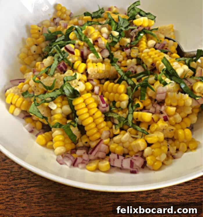 Close-up of vibrant fresh corn salad in a white bowl, highlighting the golden kernels and fresh green basil.