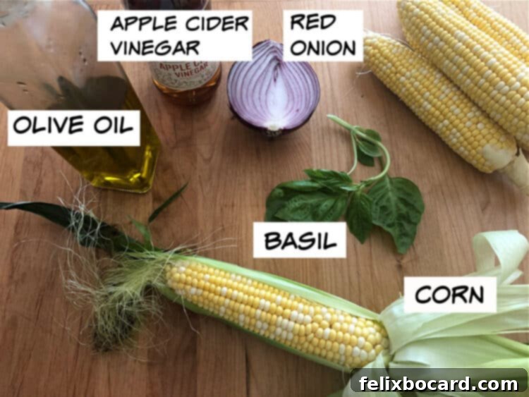 Fresh ingredients laid out for corn salad: corn cobs, red onion, basil leaves, olive oil, and apple cider vinegar.