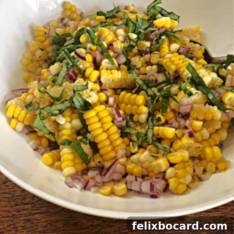 Close-up view of the corn salad with red onion and dressing, ready for basil.