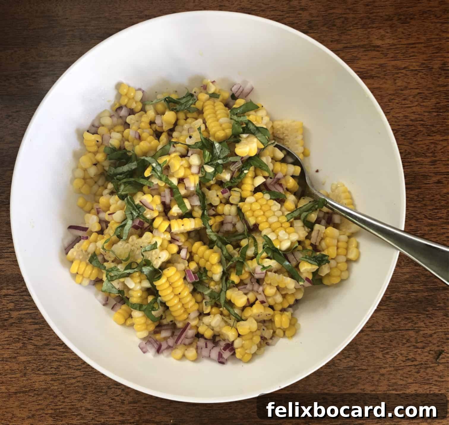 Fresh Corn Salad served in a large white bowl, garnished with basil, ready for a gathering.