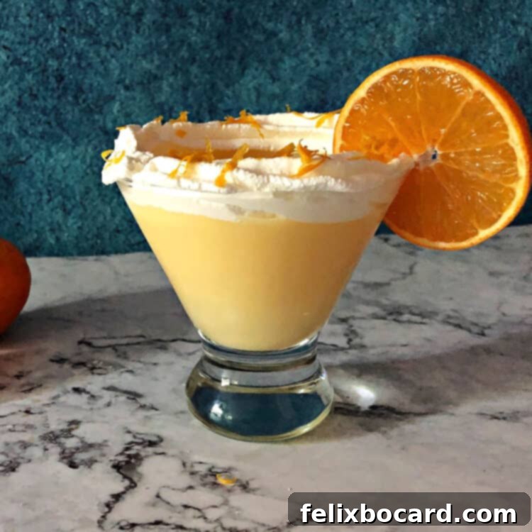 A single Orange Creamsicle Cocktail presented in an elegant martini glass, beautifully garnished with a generous swirl of whipped cream on top, ready to be enjoyed.