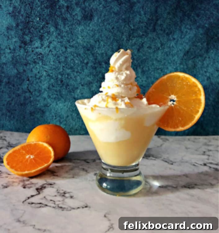 A close-up of an Orange Creamsicle Martini, spectacularly garnished with an extra-high, swirling tower of whipped cream and a hint of orange zest, looking exceptionally indulgent.