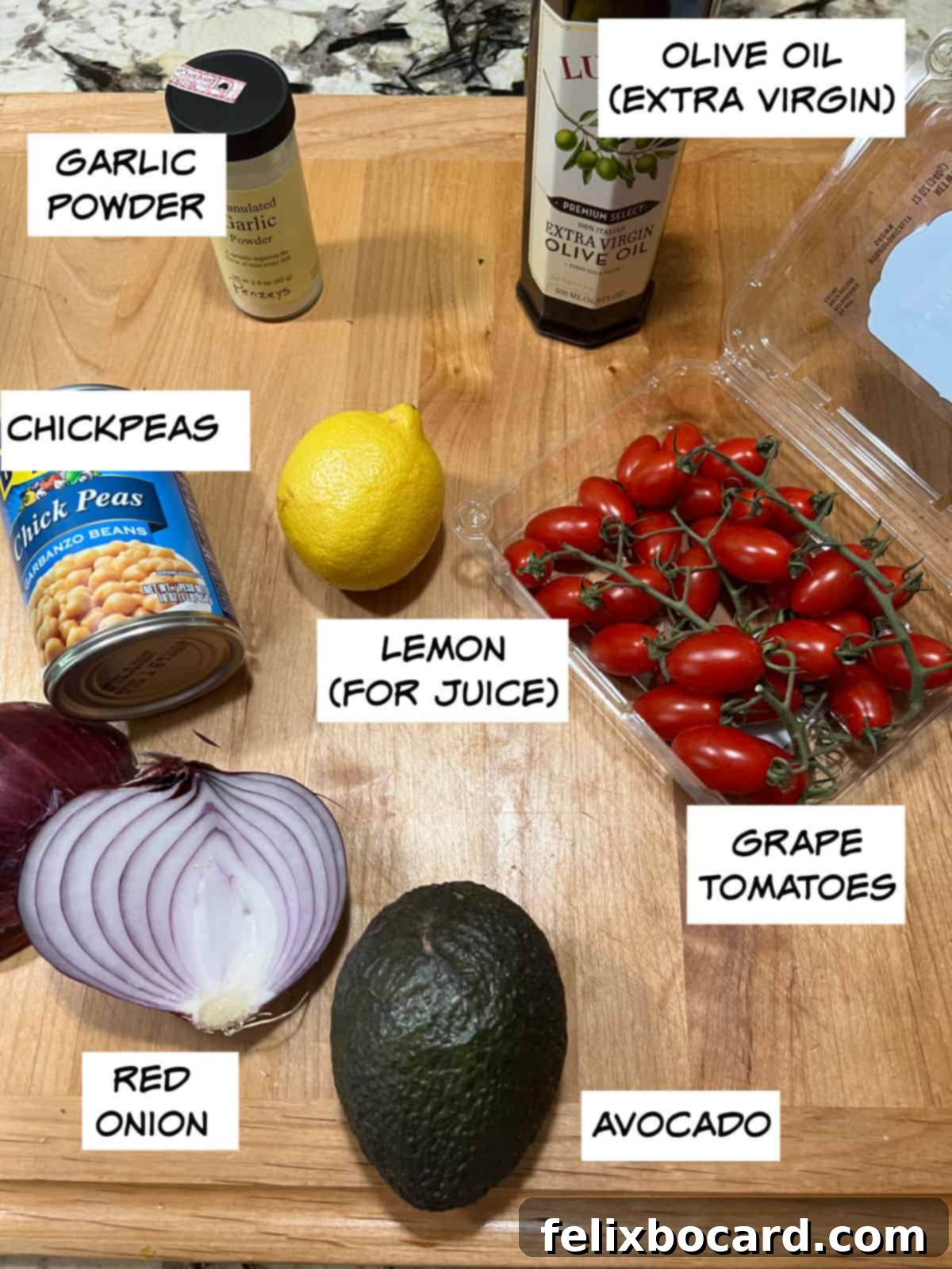 A visually appealing flat lay of the key ingredients: canned chickpeas, fresh garlic cloves, a bright yellow lemon, rich olive oil, ripe tomatoes, a creamy avocado, and a bold red onion, all set for preparing a healthy chickpea avocado salad.