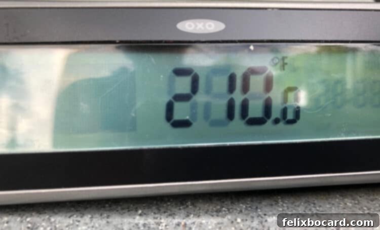 Digital thermometer showing an internal temperature of 210°F, indicating a perfectly cooked potato