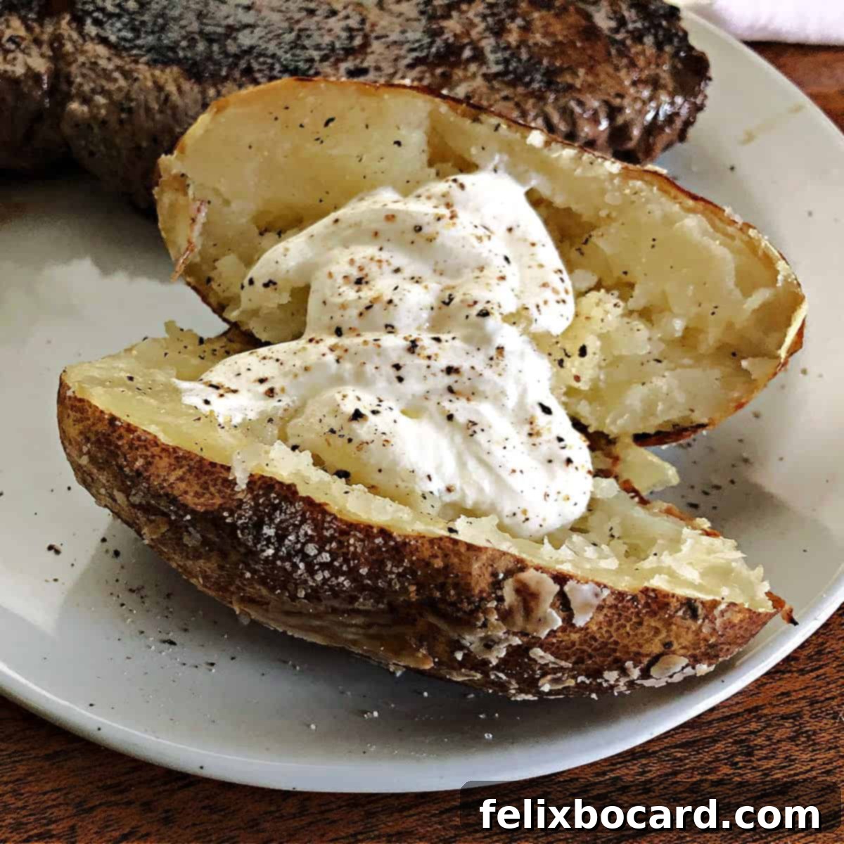 A beautifully grilled baked potato served on a white plate, ready for toppings