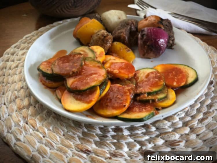 Microwaved zucchini and yellow squash in tomato sauce with Parmesan cheese on a white plate, garnished with fresh herbs.