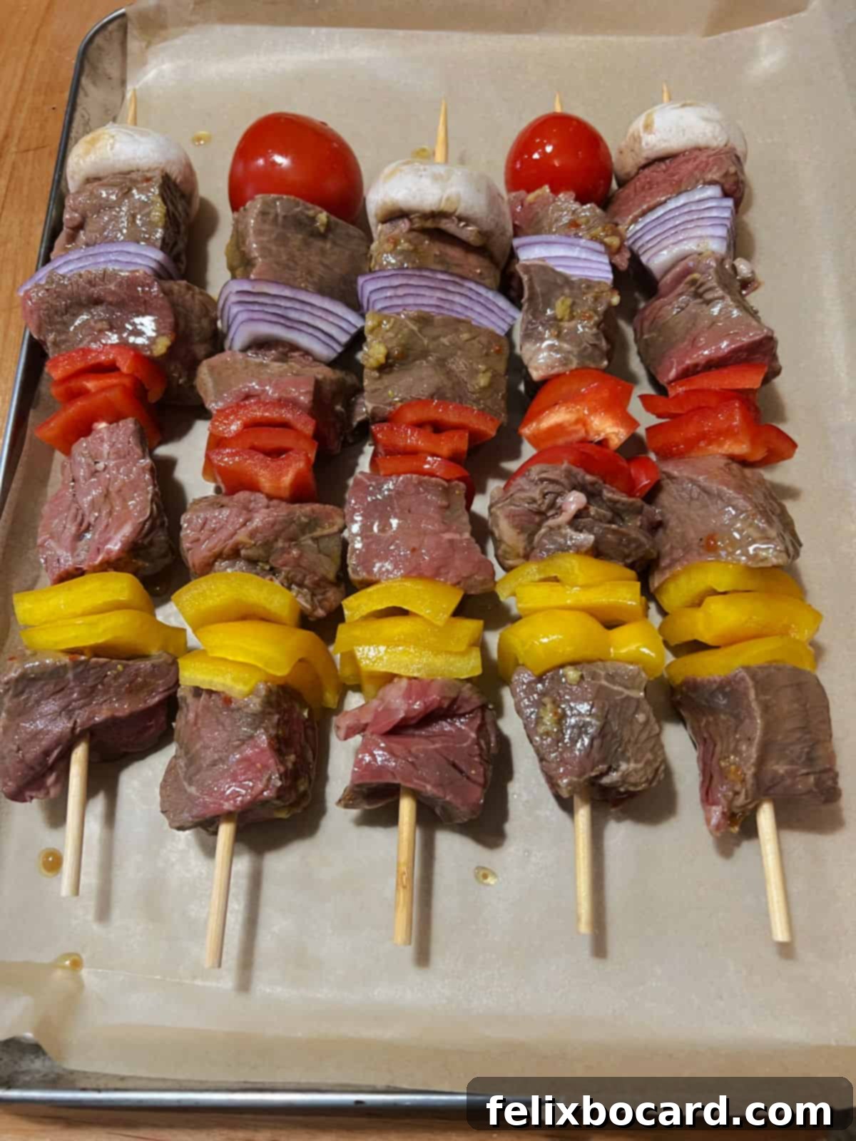 Five perfectly threaded beef and vegetable kabobs, showcasing colorful bell peppers, onions, mushrooms, and succulent beef cubes on skewers.