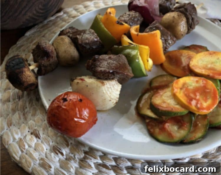 Serving of beef steak kabobs plated with tender microwave zucchini and yellow squash.