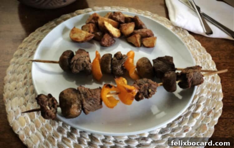 Platter of grilled beef kabobs served alongside crispy roasted potatoes, creating a hearty meal.